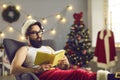 Modern Santa reading Naughty or Nice list or book with amazing ideas for winter holidays Royalty Free Stock Photo