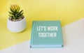 Let\'s work together written on a green notepad and a yellow and white background