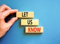 Let us know symbol. Concept words Let us know on wooden blocks on a beautiful blue table blue background. Businessman hand.