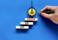 Let us know symbol. Concept words Let us know on wooden blocks on a beautiful blue table blue background. Yellow light bulb. Royalty Free Stock Photo