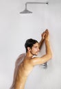 Let warm waters wash your worries away. Tired young male leaning against a shower wall taking a relaxing shower - Royalty Free Stock Photo