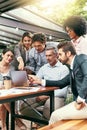 Lets explore that. a team of colleagues using a laptop together during a meeting outdoors.