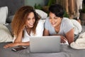 Lets find something we can both agree on. a young couple using a laptop while lying on their bed.