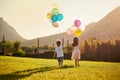 Lets get carried away together. Rearview shot of two cute little siblings holding balloons while walking outside. Royalty Free Stock Photo