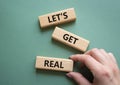 Lets get real symbol. Concept words Lets get real on wooden blocks. Beautiful grey green background. Businessman hand. Business Royalty Free Stock Photo