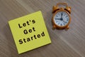 Lets get started - message with advice on yellow notepad with alarm clock Royalty Free Stock Photo