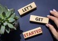 Lets get started symbol. Concept words Lets get started on wooden blocks. Beautiful deep blue background. Businessman hand.