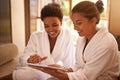 Lets get this therapy started...two friends in bathrobes using a digital tablet at a spa. Royalty Free Stock Photo