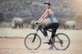 Lets get wild. Portrait of a young woman on a bicycle looking at a group of rhinos in the veld.