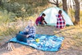 Lets go camping. Family camping. Reach destination place. Two girls pitch tent and one boy watching show on the laptop, sitting on