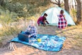 Lets go camping. Family camping. Reach destination place. Two girls pitch tent and one boy watching show on the laptop, sitting on