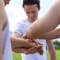 Lets just go enjoy this. young men piling their hands while standing in a huddle.