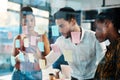 Lets make a note of this now. a diverse group of businesspeople standing and using a glass board with post-its in the Royalty Free Stock Photo