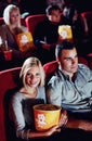 He lets me have all the popcorn. Portrait of a young girl sitting next to her date at the movies.