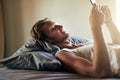 Lets see what everyone is up to this weekend...a young man texting on his cellphone while lying in bed. Royalty Free Stock Photo