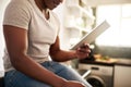 Lets see whats trending today. an unrecognizable man using a digital tablet while sitting on the kitchen counter at home