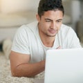 Lets see whats up in the world wide web. a relaxed young man using a laptop on the floor at home. Royalty Free Stock Photo