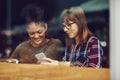 Lets see who would like to join us here...two young friends looking at something on a cellphone in a cafe. Royalty Free Stock Photo