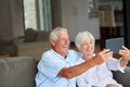 Lets show them how a couple should do a selfie. a senior couple taking a selfie with their tablet at home.