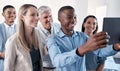 Lets show the world who we are. a group of businesspeople taking selfies together on a digital tablet in an office.