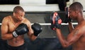 Lets take this to the next level. A focused young boxer sparring with his partner in protective gloves.