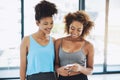 Lets tell everyone about our workout session. two young fit women having a chat while looking at a phone inside of a gym Royalty Free Stock Photo