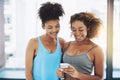 Lets time ourselves. two young fit women having a chat while looking at a phone inside of a gym before a workout session Royalty Free Stock Photo