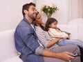 Lets watch some cartoons. a young family sitting together on a sofa watching television. Royalty Free Stock Photo