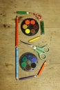 a letter B made of coloring pencils, watercolor paints and scissors on a wooden table