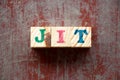 Letter block in word JIT Abbreviation of just in time on red wood background