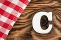 Letter C of the alphabet - Red checkered cloth tablecloth on rustic wood background. Text space Royalty Free Stock Photo