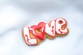 Letter cookies for Valentine`s day or for a wedding day on the background of white lightweight fabric. Royalty Free Stock Photo