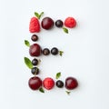 Fresh fruits pattern of letter E english alphabet from natural ripe berries - black currant, cherries, raspberry, mint Royalty Free Stock Photo