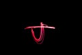 Letter J written with light paint photography technique on black background.
