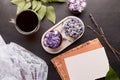 Letter mockup, craft envelope. Coffee time, purple floral cupcakes and cup of coffee. No sugar sweet dessert among lilac