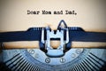 Letter for parents beginning with Dear mom and dad text typed by vintage typewriter machine