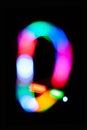 Letter Q. Glowing letters on dark background. Abstract light painting at night. Creative artistic colorful bokeh. New Year.