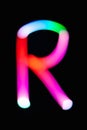 Letter R. Glowing letters on dark background. Abstract light painting at night. Creative artistic colorful bokeh. New Year. Royalty Free Stock Photo