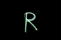 Letter R written with light paint photography technique on black background.