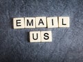 Letter tiles on black slate background spelling Email Us