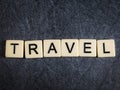 Letter tiles on black slate background spelling Travel