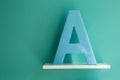 Letter A turquoise color on a white shelf