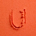Letter U written on orange sand