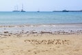 Lettering Atlantic ocean written on the beach wet sand. Boats on the water. Cascais, Portugal Royalty Free Stock Photo