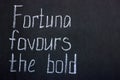 Lettering on a dark blackboard in white chalk fortuna favored the bold Royalty Free Stock Photo