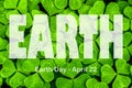 Lettering Earth Day April 22 on the background of clover. Earth day concept, protection of the planet from pollution, improvement