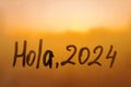 lettering Hola in Spanish is hello in english and numbers 2024 paint with finger with streaks of water on splashed by