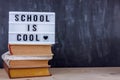 Lettering School is cool on a pile of books. Black writing desk on background