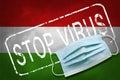 Lettering stamp Stop Virus and medical mask on Hungary flag. Return of the coronavirus. New jump in incidence. Strain Omicron and