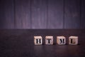 The letters abbreviation html on wooden cubes, on a dark background, light wooden cubes signs Royalty Free Stock Photo